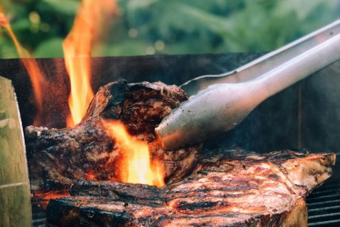 gray metal tong and grilled meat with fire